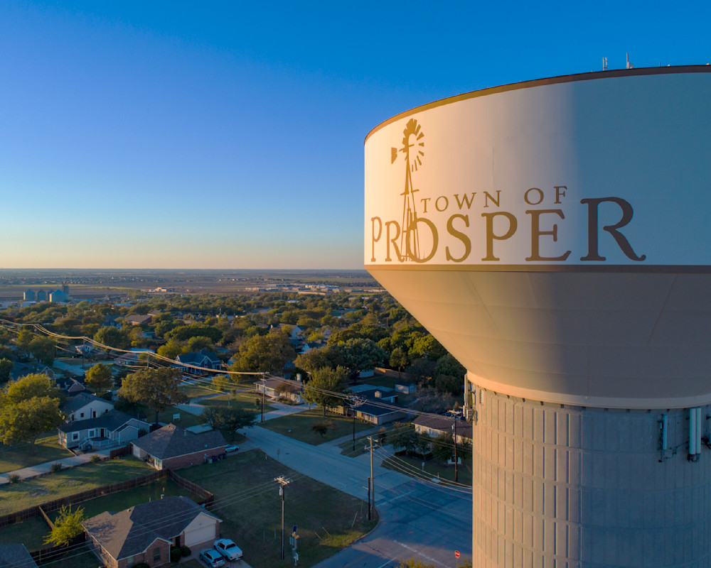 Town of Prosper water tower with windmill logo overlooking residential neighborhoods at sunset