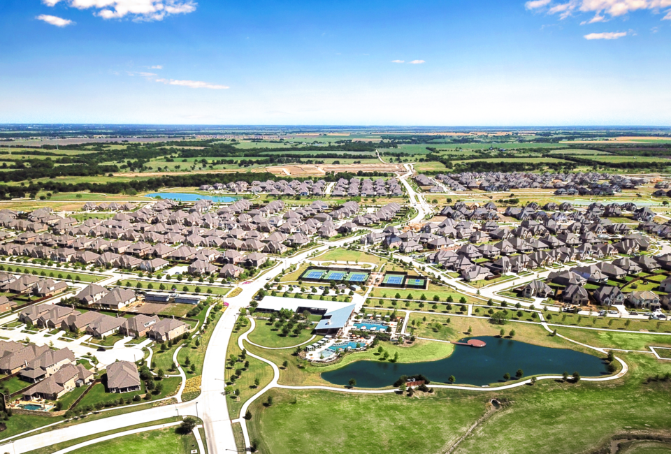 Aerial view of Windsong Ranch in Prosper, Texas, showing homes, amenity center, sports courts, green space, and ponds