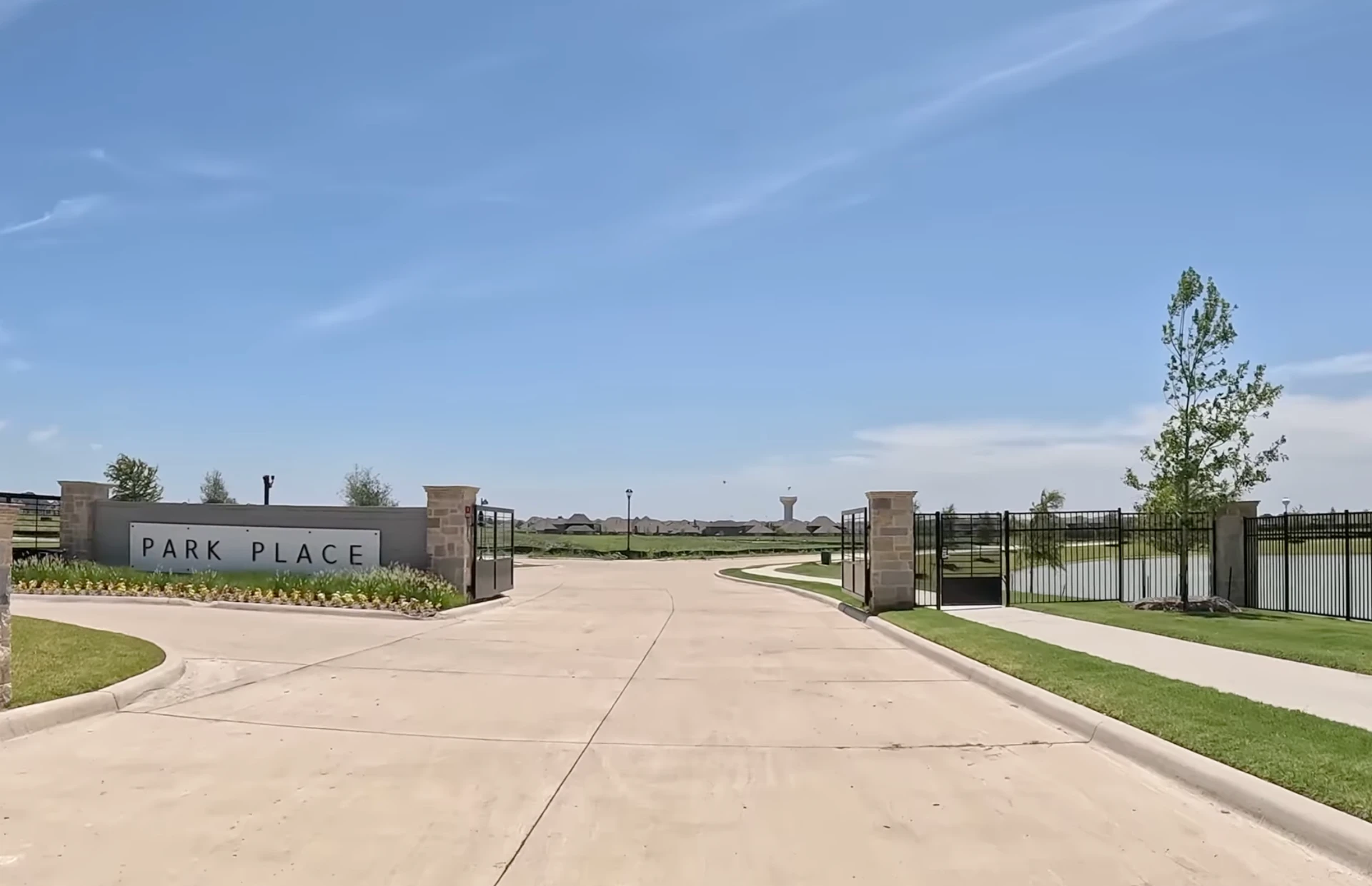 Gated entrance to Park Place in Prosper, Texas, with stone pillars and an open black metal driveway gate